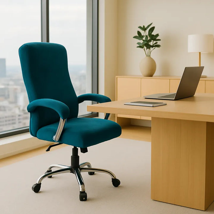Chaise de bureau recouverte d’une housse en velours bleu canard, placée dans un grand bureau moderne et lumineux avec une large baie vitrée offrant une vue sur la ville. Le bureau en bois clair, décoré avec un ordinateur portable, un carnet et une plante verte, crée une ambiance élégante, professionnelle et haut de gamme.