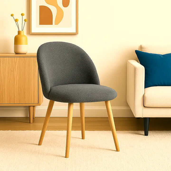 Une chaise design recouverte d’une housse en tissu jacquard gris, mise en valeur dans un intérieur minimaliste et luxueux. Le décor présente des murs beige clair, un sol en bois naturel et une lumière douce et éclatante, créant une atmosphère élégante et raffinée.