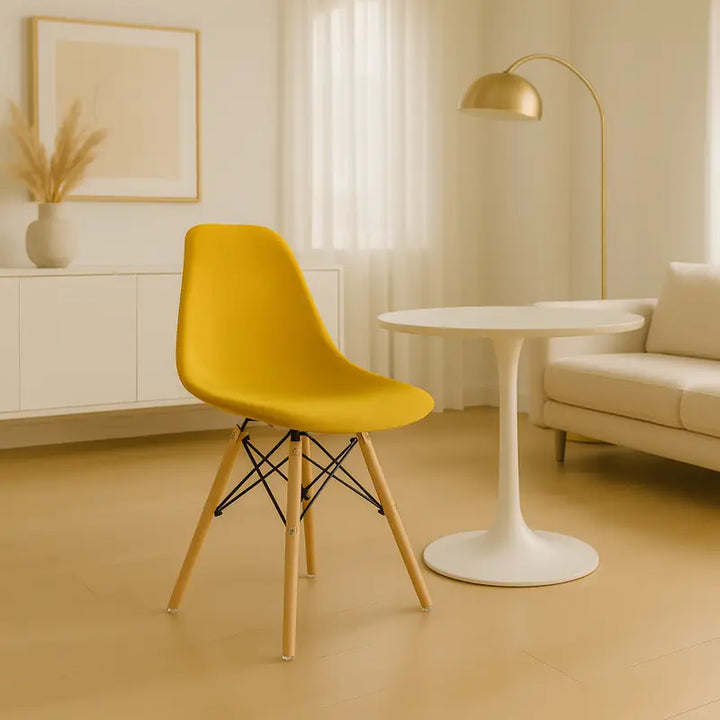 Intérieur scandinave lumineux et minimaliste avec une chaise jaune moutarde tournée vers la gauche, devant une table ronde blanche et un canapé beige dans une ambiance élégante et moderne.