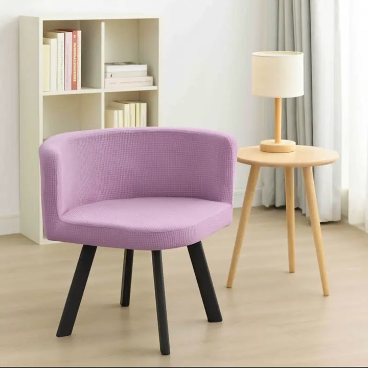 Fauteuil scandinave triangulaire recouvert d’une housse en jacquard lilas clair, placé dans un coin lecture moderne et lumineux avec une petite bibliothèque, une lampe design et un coin salon de thé, sur un parquet clair dans une ambiance harmonieuse et apaisante.