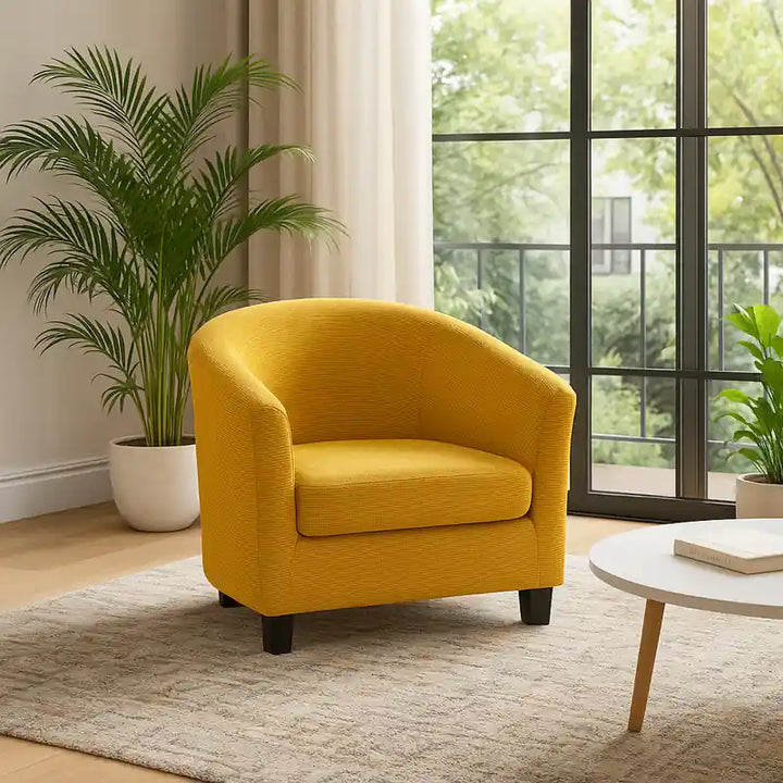 Salon luxueux et lumineux avec un fauteuil crapaud recouvert d’une housse jaune dorée élégante, placé sur un tapis doux près d’une grande baie vitrée, entouré de plantes vertes et d’une décoration moderne raffinée.