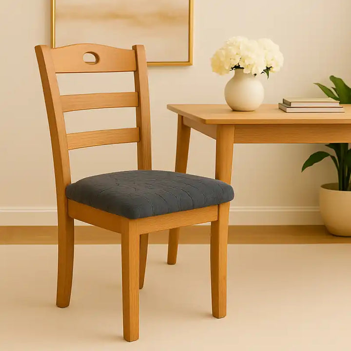 Une salle à manger lumineuse et raffinée avec une table en bois clair et une chaise en bois habillée d’une housse de siège en jacquard gris anthracite à motifs floraux. L’ambiance est naturelle et élégante, éclairée par une lumière douce