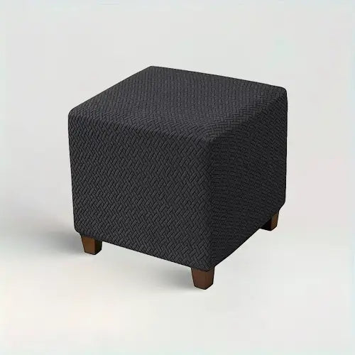 Housse de repose pied carré en jacquard effet tressé Penelope de couleur noir sur fond beige 